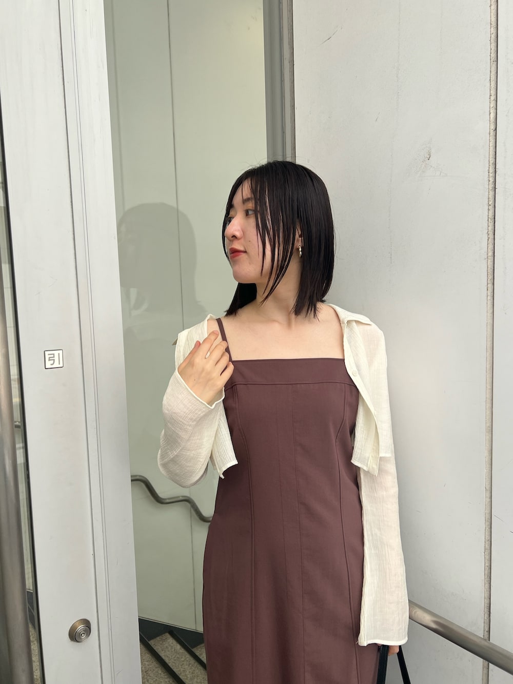 ブラック系のショルダーバッグ、ブラウン系のワンピース、ブラック系のブーツを着用したレディースの秋コーディネートの3枚目の写真