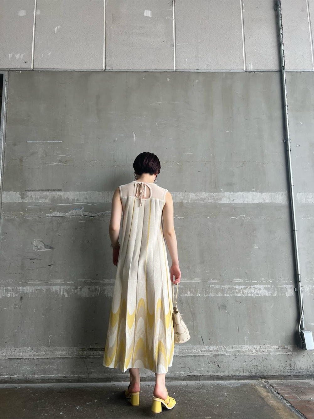 イエロー系のサンダル、イエロー系のワンピース、シルバー系のピアス（両耳用）を着用したレディースの夏コーディネートの3枚目の写真