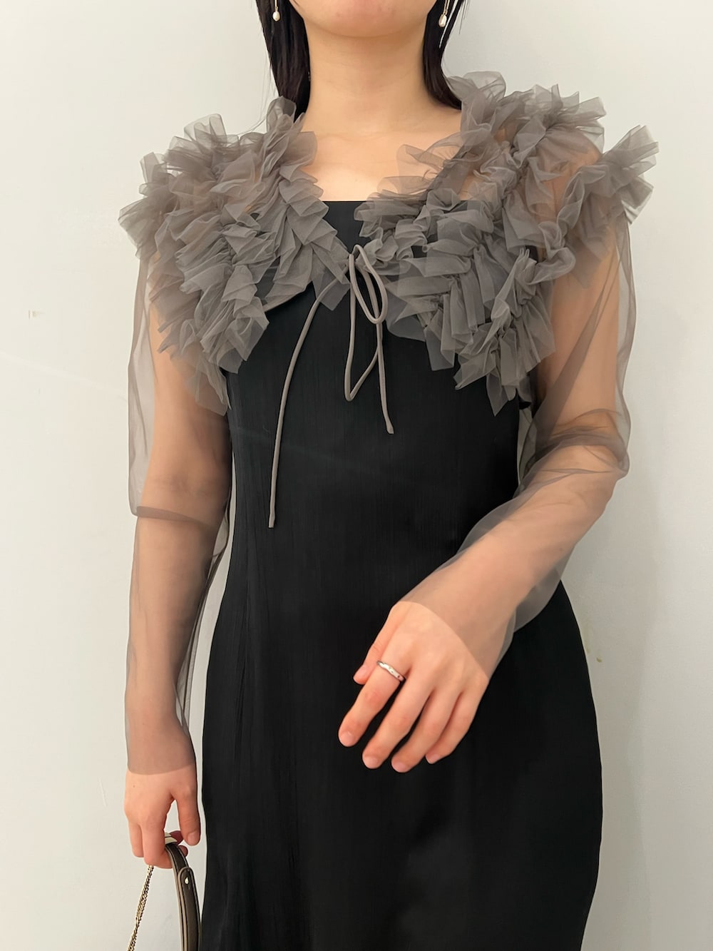 グレー系のドレス、ゴールド系のクラッチバッグ、ゴールド系のパンプスを着用したレディースの春コーディネートの4枚目の写真