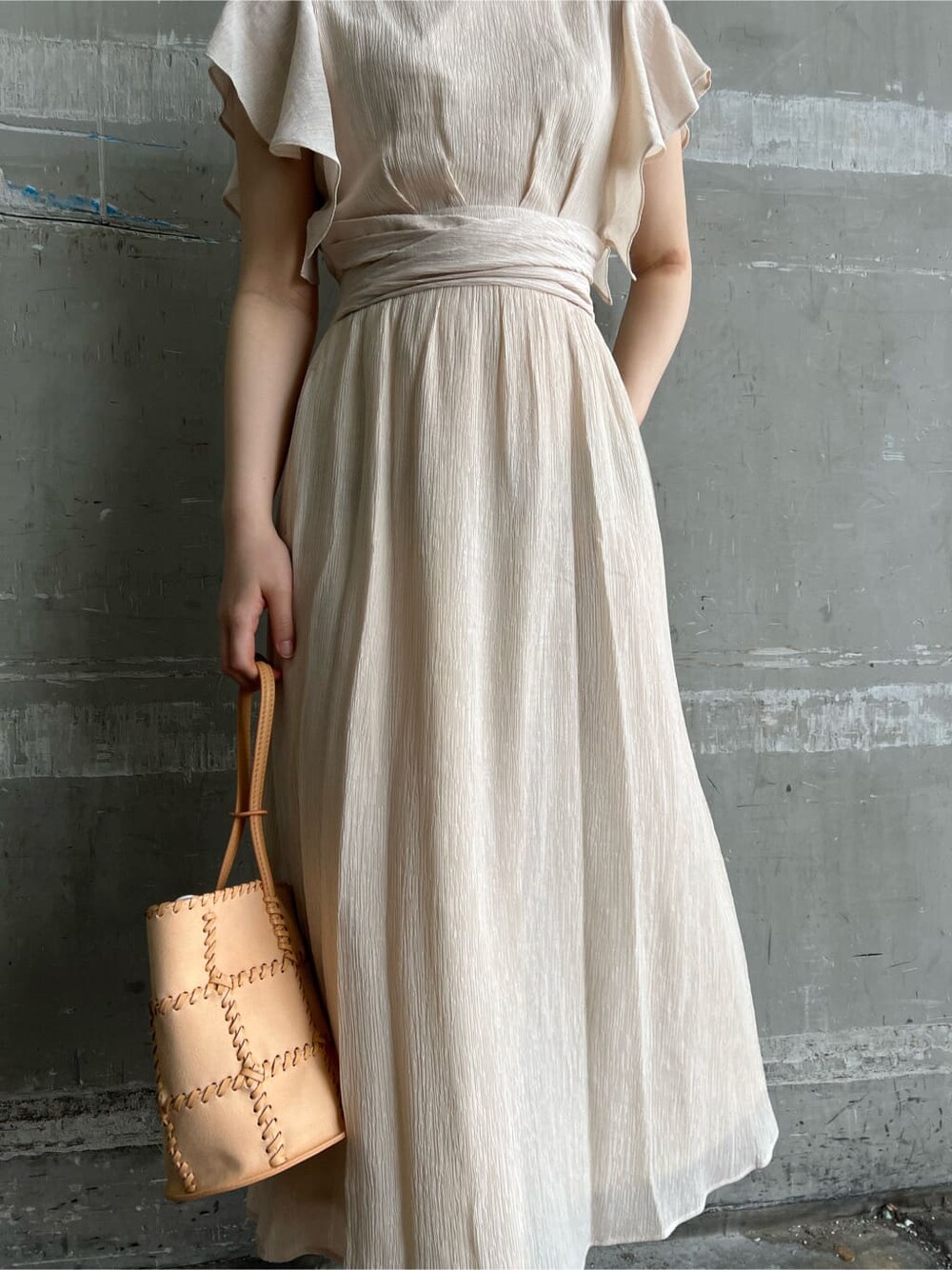 ホワイト系のワンピース、ブラウン系のパンプス、オレンジ系のショルダーバッグを着用したレディースの春コーディネートの6枚目の写真