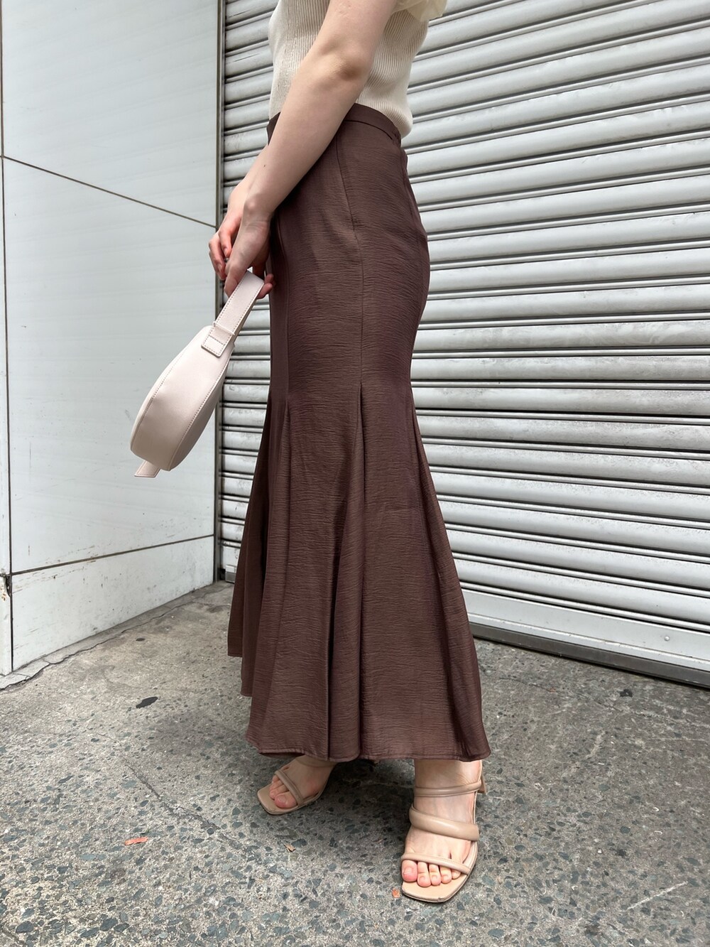 ベージュ系のサンダル、ブラウン系のスカート、ホワイト系のハンドバッグを着用したレディースの夏コーディネートの8枚目の写真