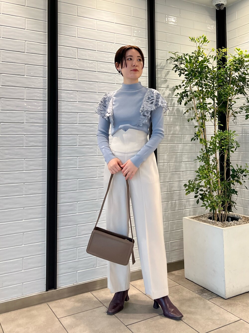 ベージュ系のノーカラーコート、ベージュ系のショルダーバッグ、レッド系のブーツを着用したレディースの冬コーディネートの6枚目の写真