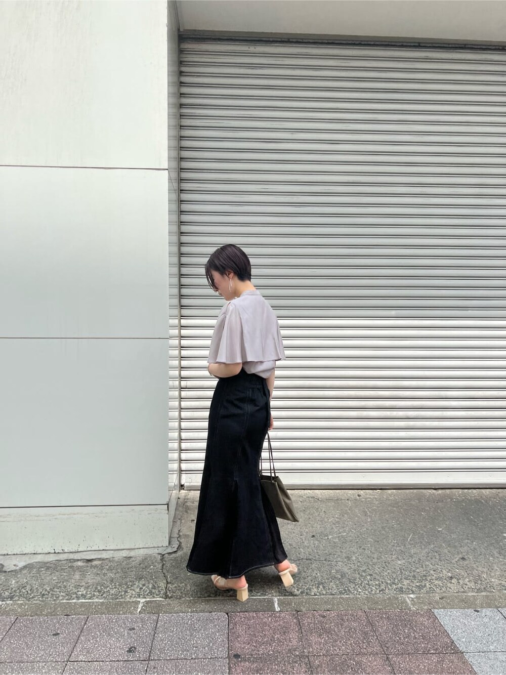 ベージュ系のハンドバッグ、ブラック系のスカート、その他のサンダルを着用したレディースの夏コーディネートの2枚目の写真