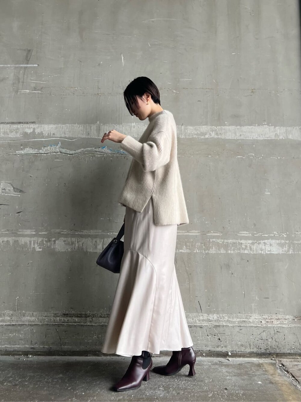 レッド系のブーツ、グレー系のスカート、パープル系のハンドバッグを着用したレディースの秋コーディネートの2枚目の写真