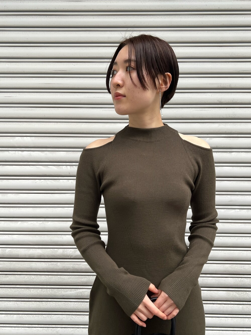 レッド系のブーツ、ブラック系のハンドバッグ、グリーン系のワンピースを着用したレディースの冬コーディネートの4枚目の写真