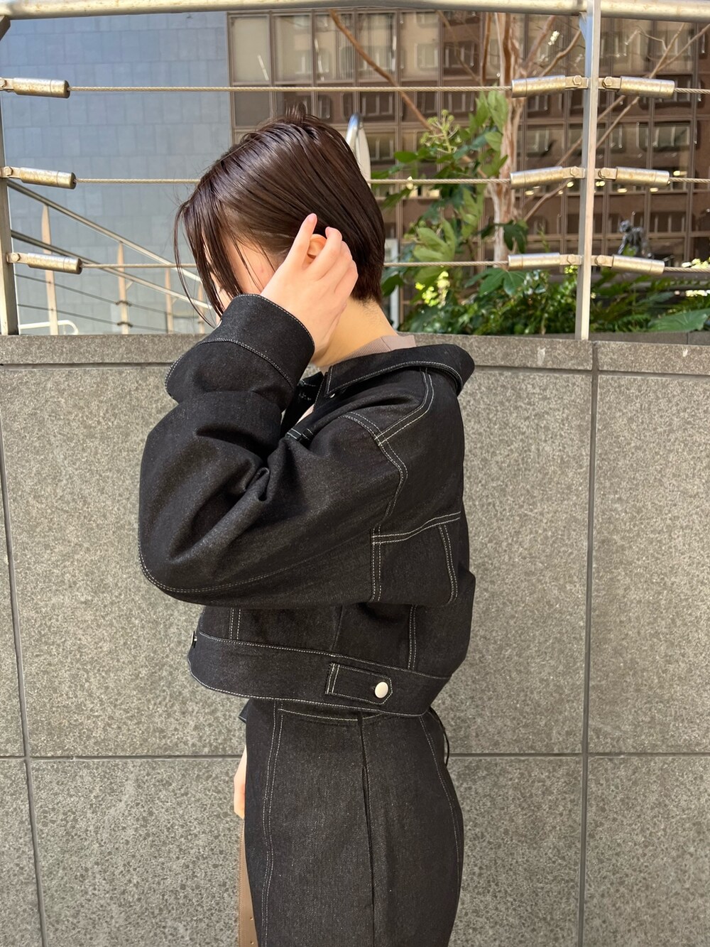 ブラック系のデニムスカート、ベージュ系のショルダーバッグ、レッド系のブーツを着用したレディースの冬コーディネートの2枚目の写真