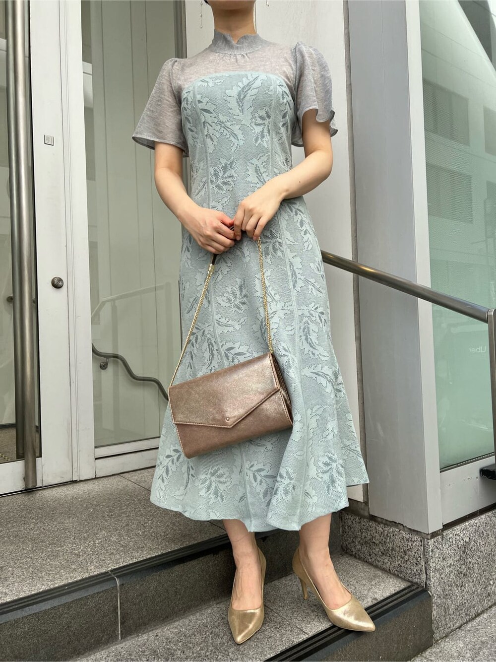 ゴールド系のクラッチバッグ、ゴールド系のパンプス、ブルー系のドレスを着用したレディースの秋コーディネートの4枚目の写真