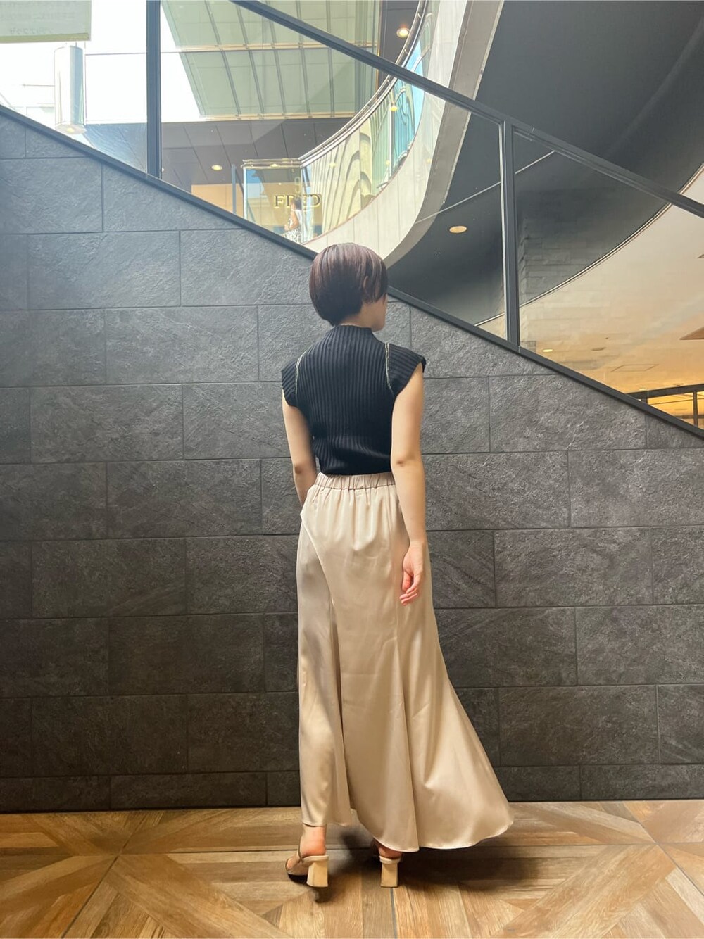 グリーン系のサンダル、ブラック系のニット/セーター、ホワイト系のスカートを着用したレディースの夏コーディネートの2枚目の写真