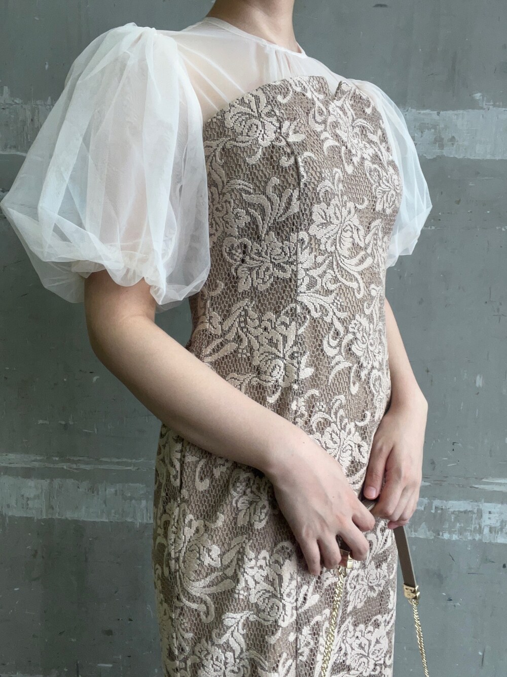 ベージュ系のドレス、ブラウン系のクラッチバッグ、ゴールド系のパンプスを着用したレディースの秋コーディネートの5枚目の写真