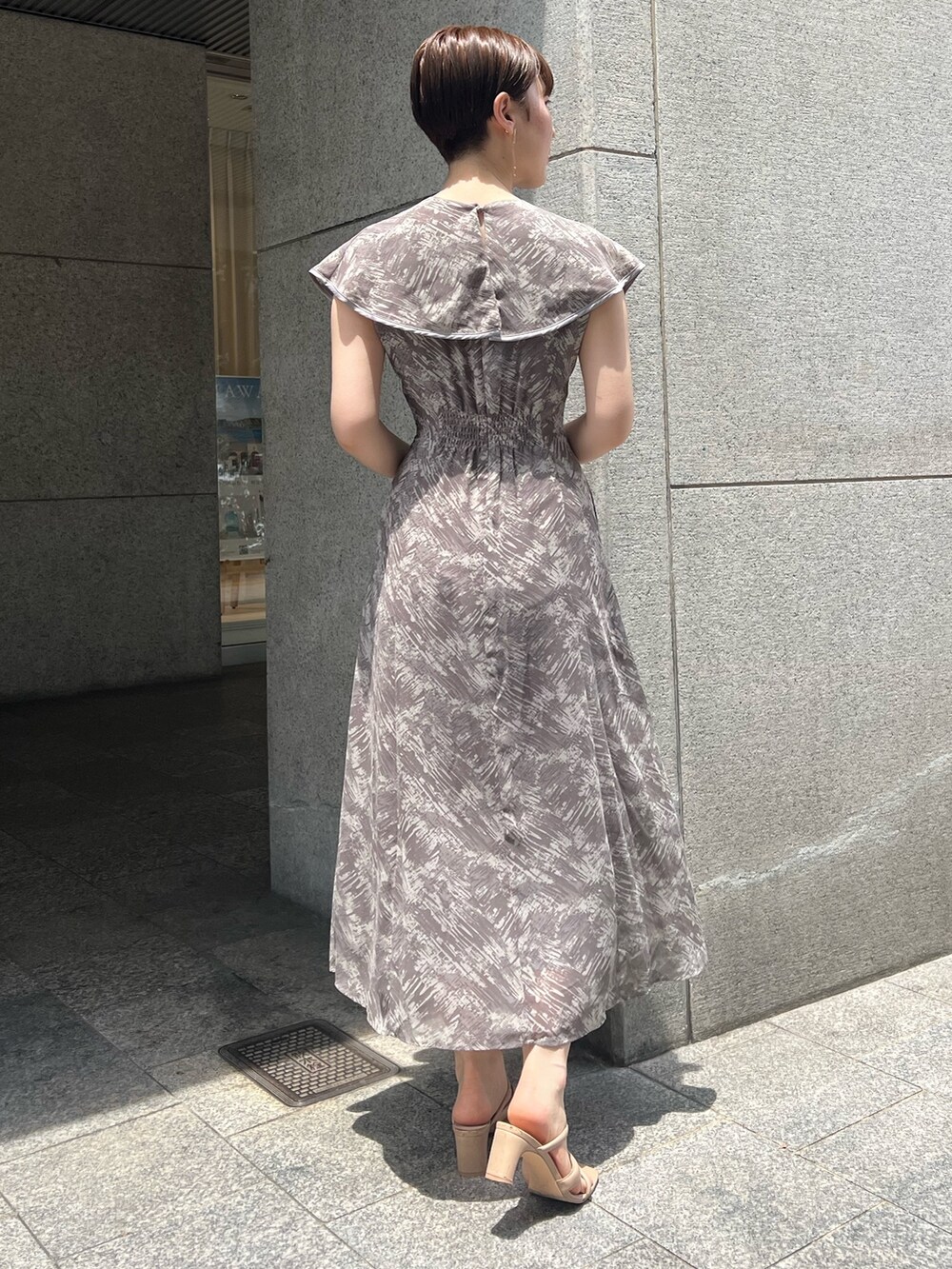 ホワイト系のハンドバッグ、ベージュ系のサンダル、グレー系のワンピースを着用したレディースの夏コーディネートの3枚目の写真