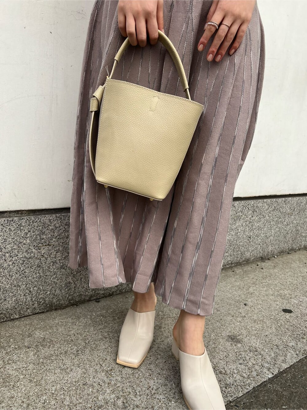 ホワイト系のノーカラーコート、グレー系のワンピース、ホワイト系のサンダルを着用したレディースの冬コーディネートの9枚目の写真