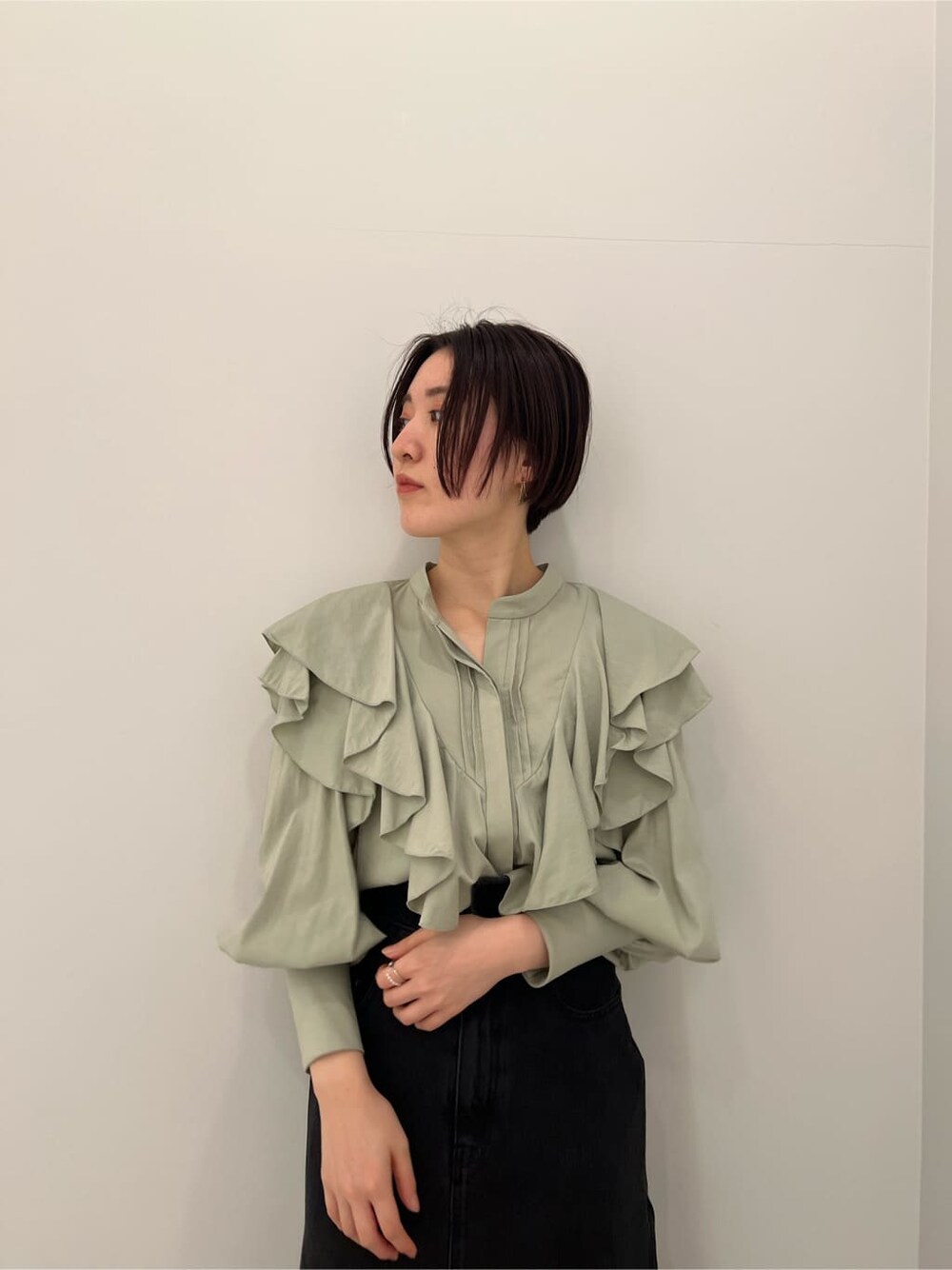 ベージュ系のその他シューズ、ブラック系のデニムスカート、グリーン系のシャツ/ブラウスを着用したレディースの冬コーディネートの3枚目の写真