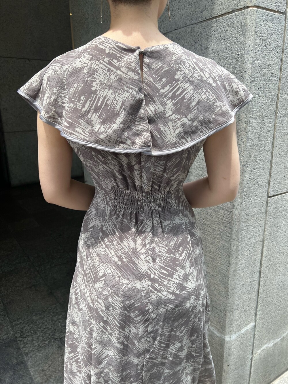 ホワイト系のハンドバッグ、ベージュ系のサンダル、グレー系のワンピースを着用したレディースの夏コーディネートの6枚目の写真