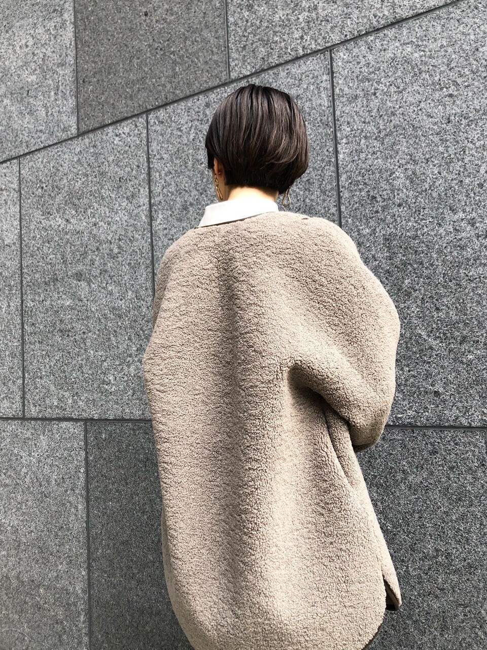 ベージュ系のムートンコート、グレー系のニット/セーター、ゴールド系のピアス（両耳用）を着用したレディースの冬コーディネートの4枚目の写真