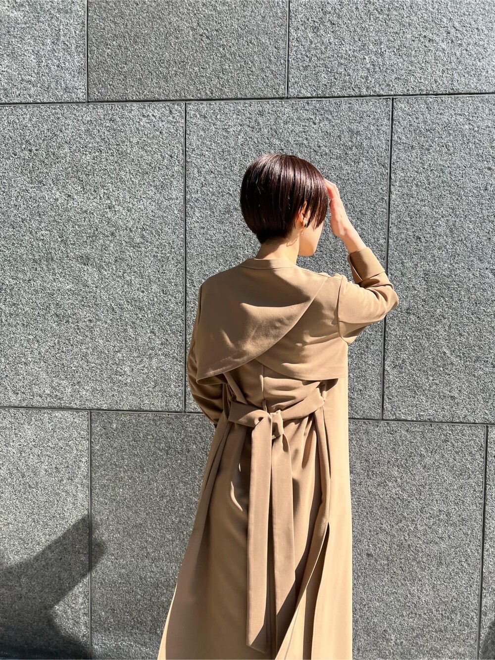 ブラウン系のクラッチバッグ、ベージュ系のその他アウター、パープル系のドレスを着用したレディースの冬コーディネートの8枚目の写真