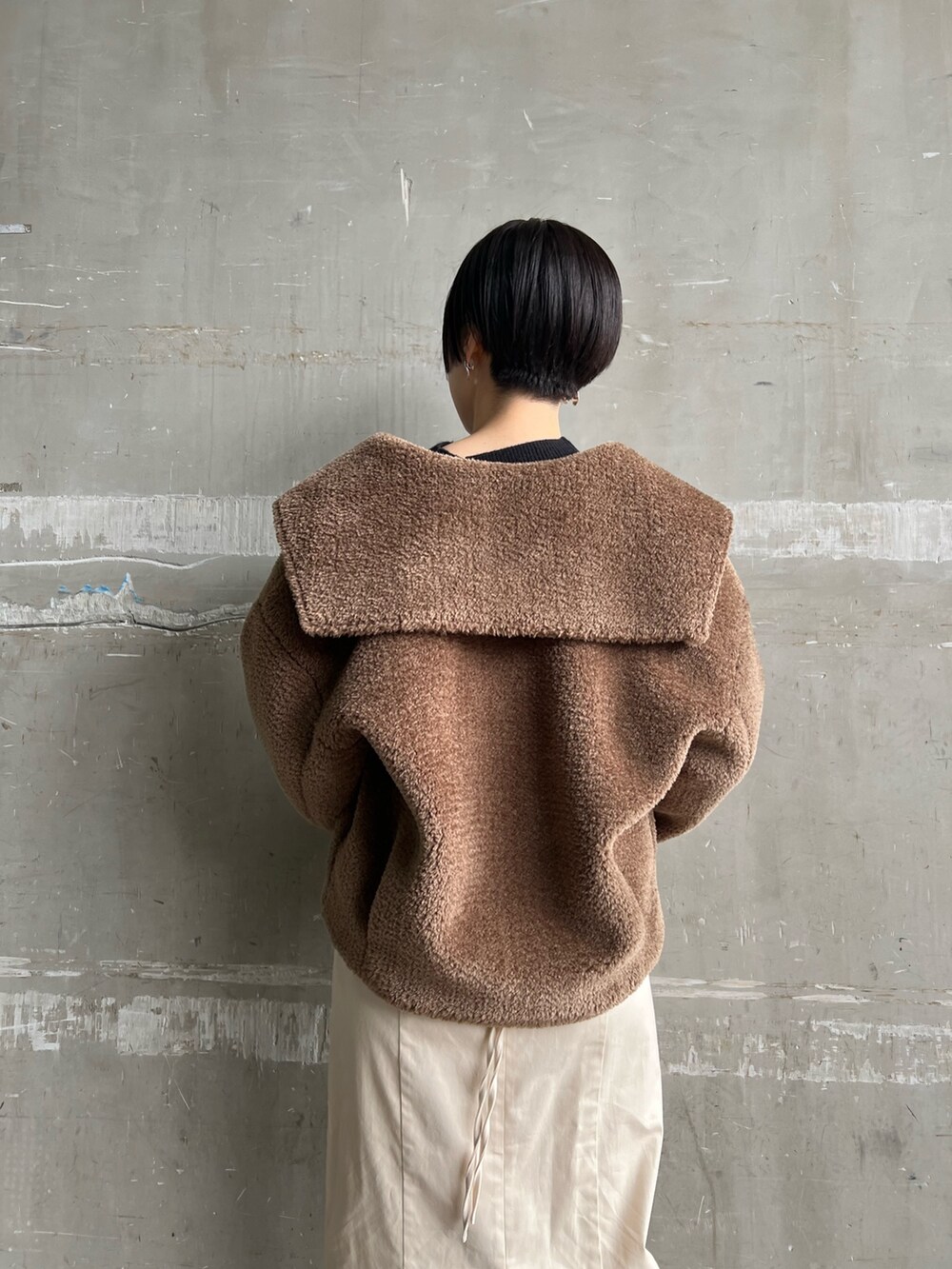 レッド系のブーツ、ホワイト系のスカート、ブラウン系のブルゾンを着用したレディースの冬コーディネートの10枚目の写真