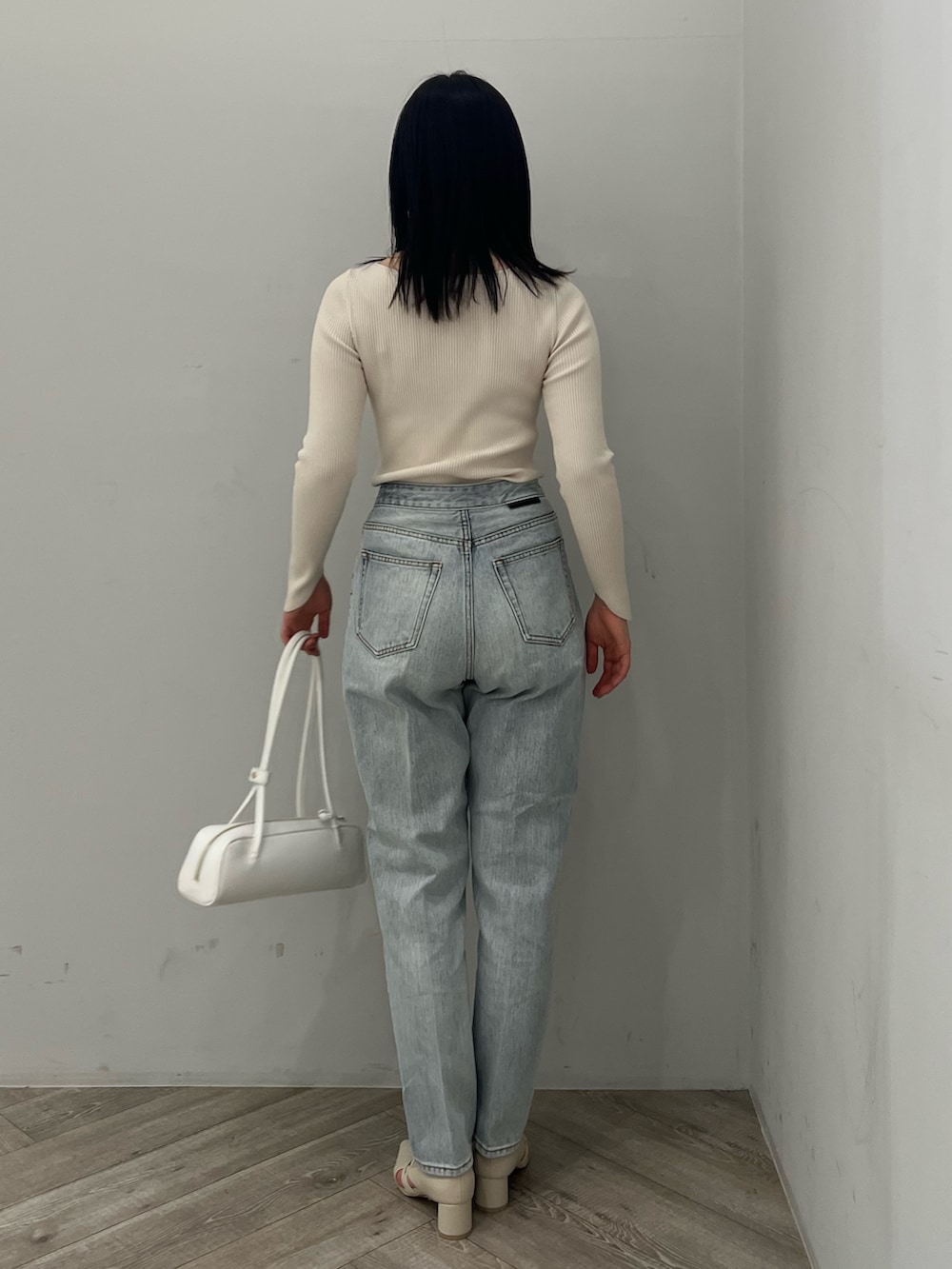 ホワイト系のニット/セーター、ブルー系のデニムパンツ、ホワイト系のパンプスを着用したレディースの春コーディネートの2枚目の写真
