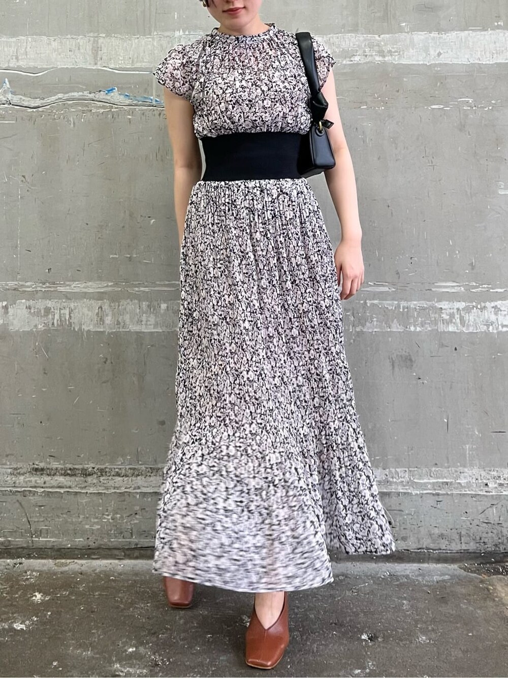 ブラウン系のパンプス、ブラック系のワンピース、ブラック系のハンドバッグを着用したレディースの夏コーディネートの3枚目の写真