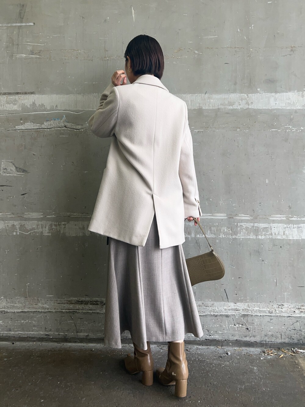 ベージュ系のブーツ、ホワイト系のニット/セーター、ホワイト系のテーラードジャケットを着用したレディースの冬コーディネートの2枚目の写真