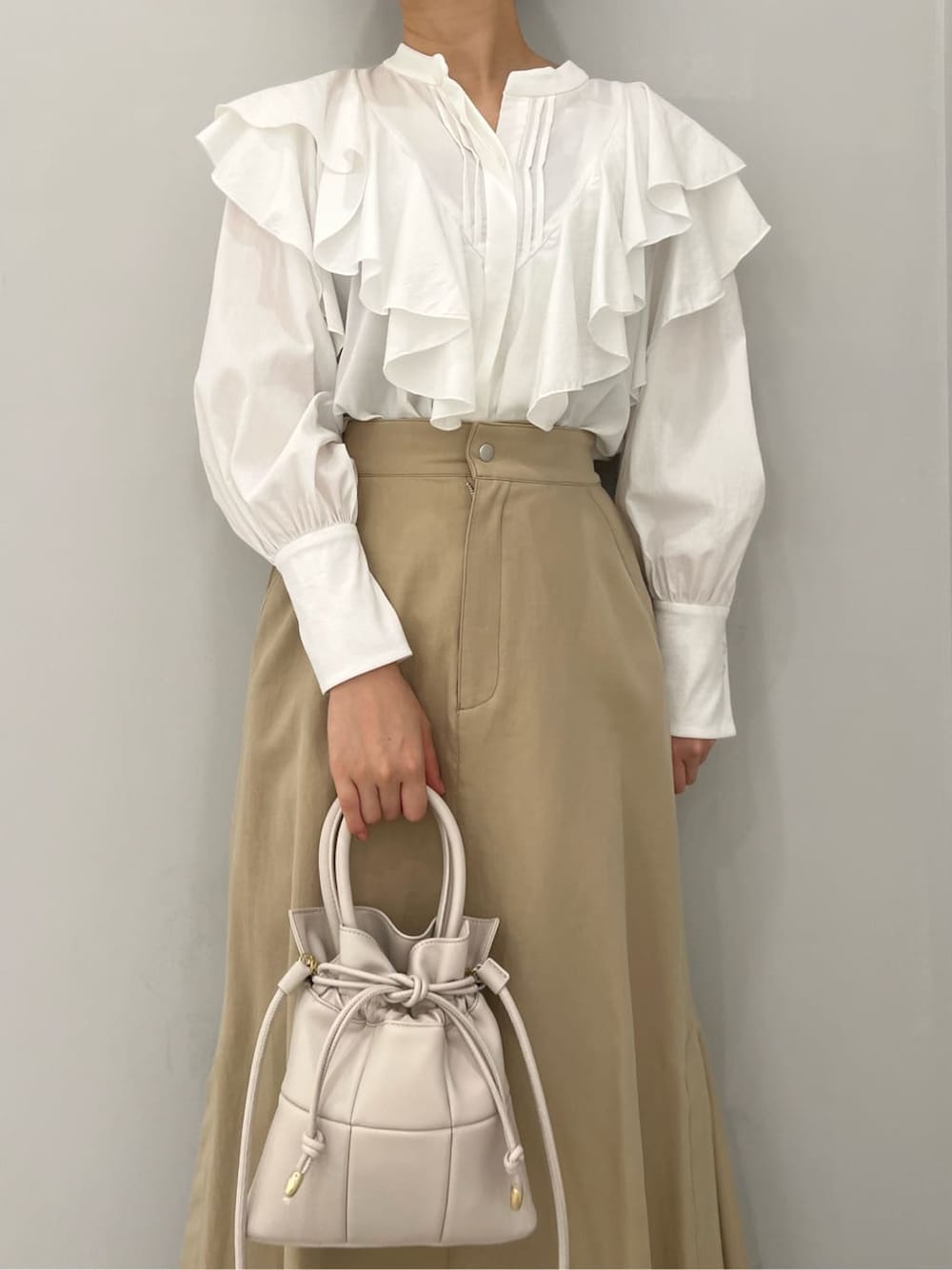 ベージュ系のスカート、レッド系のブーツ、ホワイト系のハンドバッグを着用したレディースの秋コーディネートの4枚目の写真