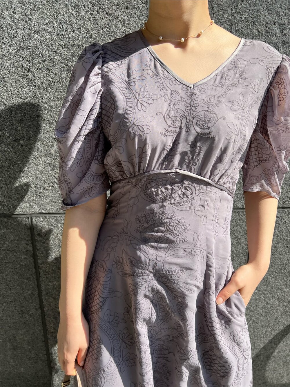 ブラウン系のクラッチバッグ、ベージュ系のその他アウター、パープル系のドレスを着用したレディースの冬コーディネートの6枚目の写真