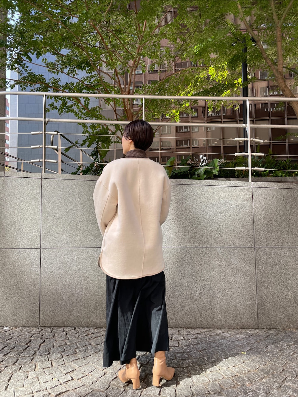 ベージュ系のその他シューズ、ホワイト系のその他アウター、ブラック系のスカートを着用したレディースの秋コーディネートの2枚目の写真