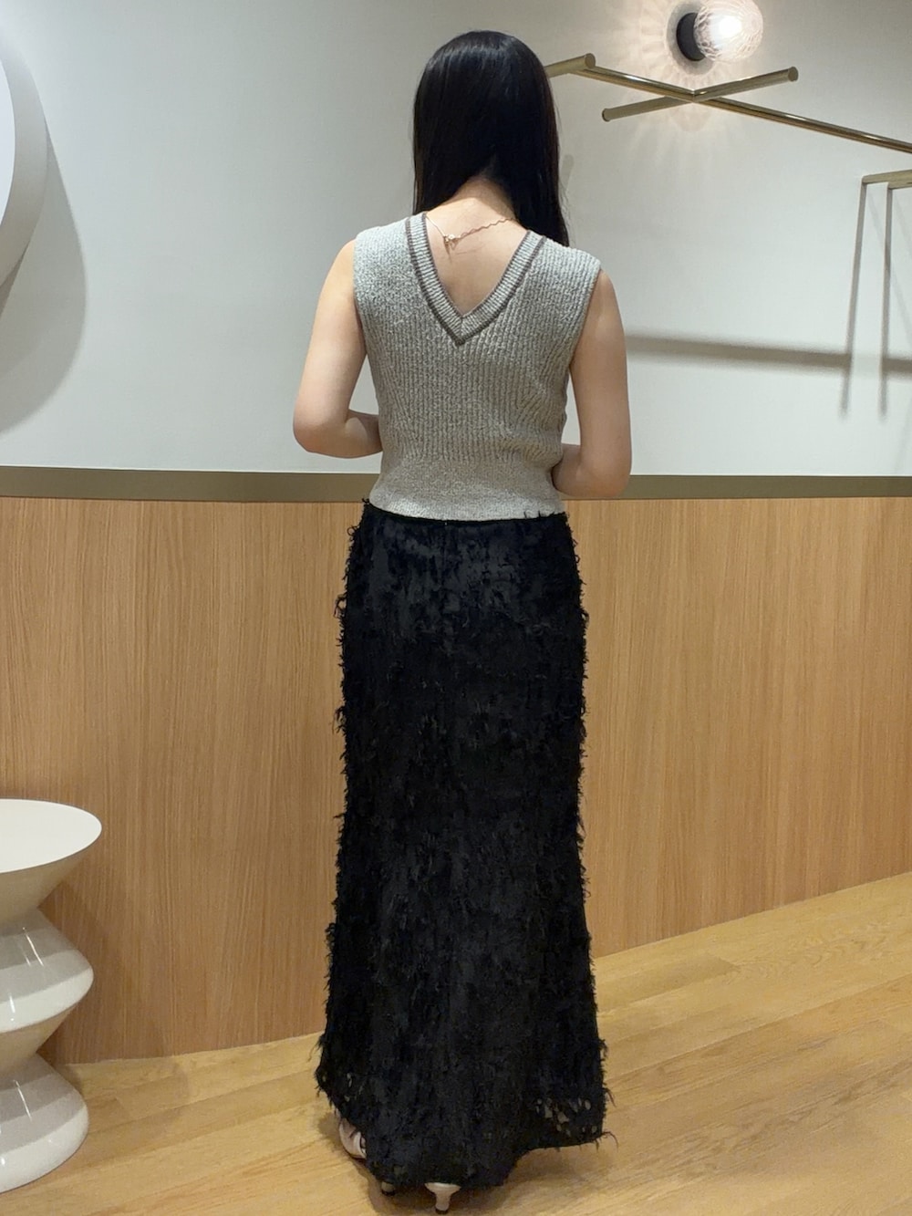 ブラック系のスカート、ベージュ系のニット/セーター、ベージュ系のサンダルを着用したレディースの春コーディネートの2枚目の写真
