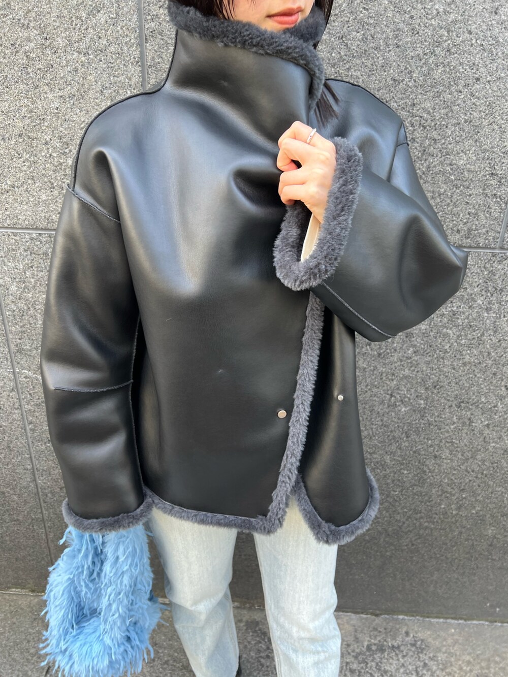 グレー系のムートンコート、ブルー系のデニムパンツを着用したレディースの冬コーディネートの5枚目の写真