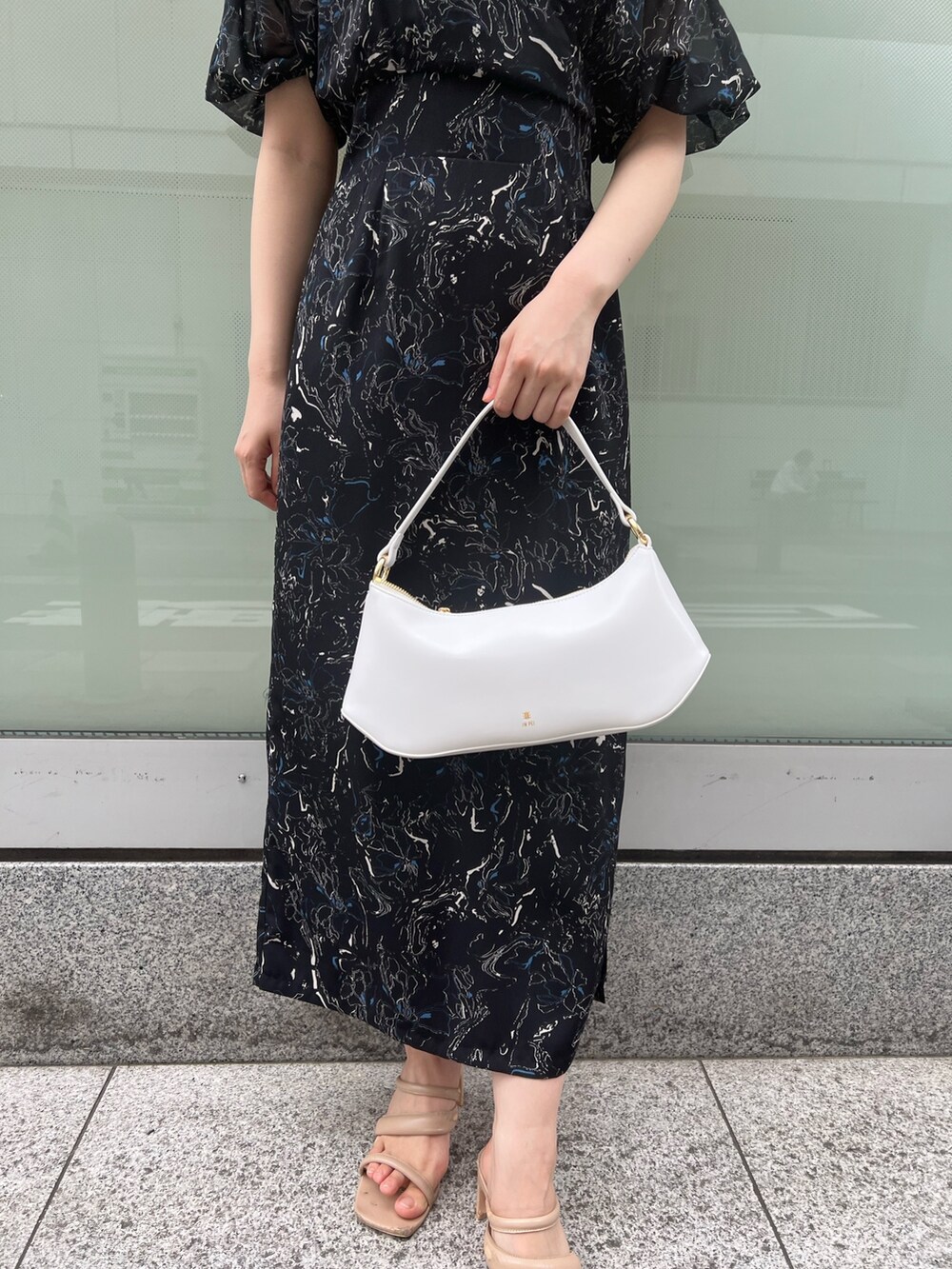 ベージュ系のサンダル、ホワイト系のハンドバッグ、ブラック系のワンピースを着用したレディースの夏コーディネートの6枚目の写真