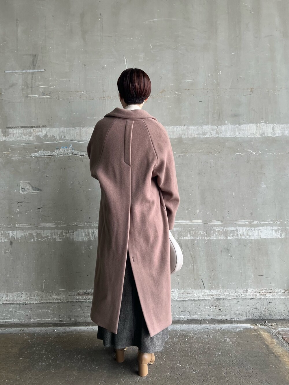 ブラウン系のスカート、ベージュ系のブーツ、ブラウン系のチェスターコートを着用したレディースの秋コーディネートの2枚目の写真