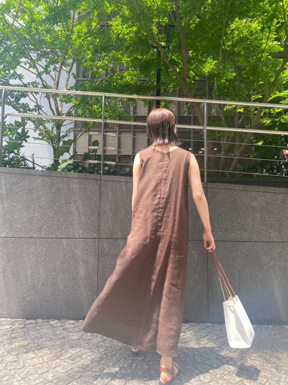 ホワイト系のハンドバッグ、ブラウン系のサンダル、ブラウン系のワンピースを着用したレディースの夏コーディネートの2枚目の写真