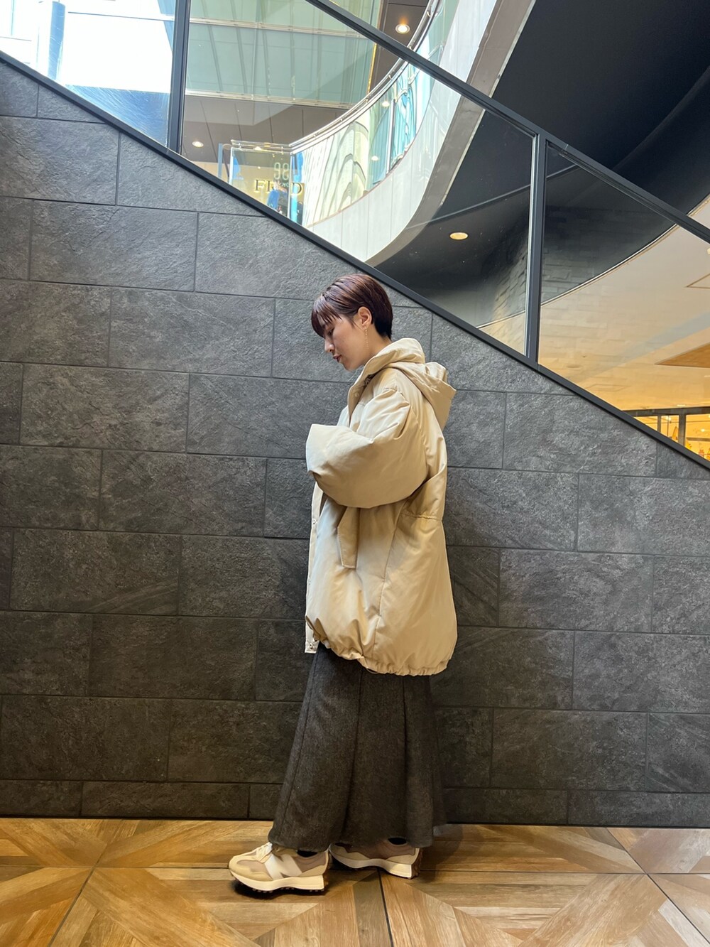 ベージュ系のスニーカー、ブラウン系のスカート、ベージュ系のダウンジャケット/コートを着用したレディースの秋コーディネートの2枚目の写真