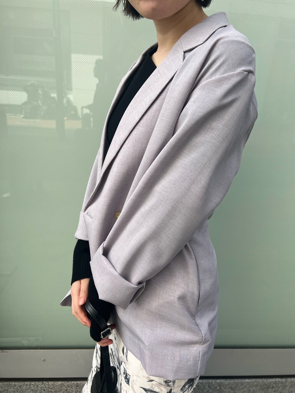 ブラック系のスニーカー、ブラック系のニット/セーター、パープル系のテーラードジャケットを着用したレディースの春コーディネートの3枚目の写真