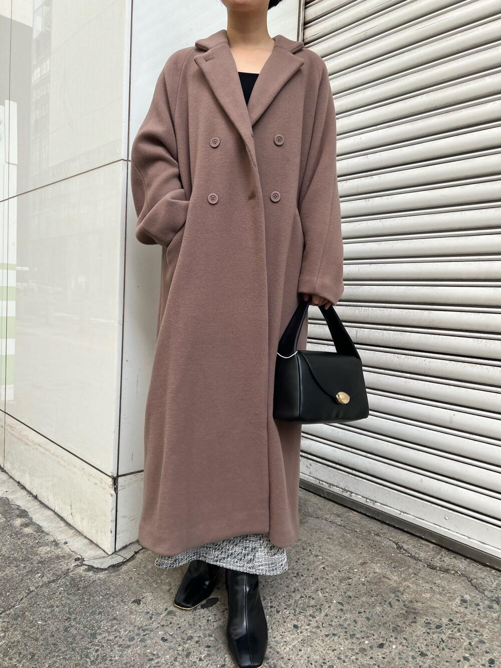 ブラック系のニット/セーター、ブラウン系のチェスターコート、ブラック系のハンドバッグを着用したレディースの冬コーディネートの2枚目の写真