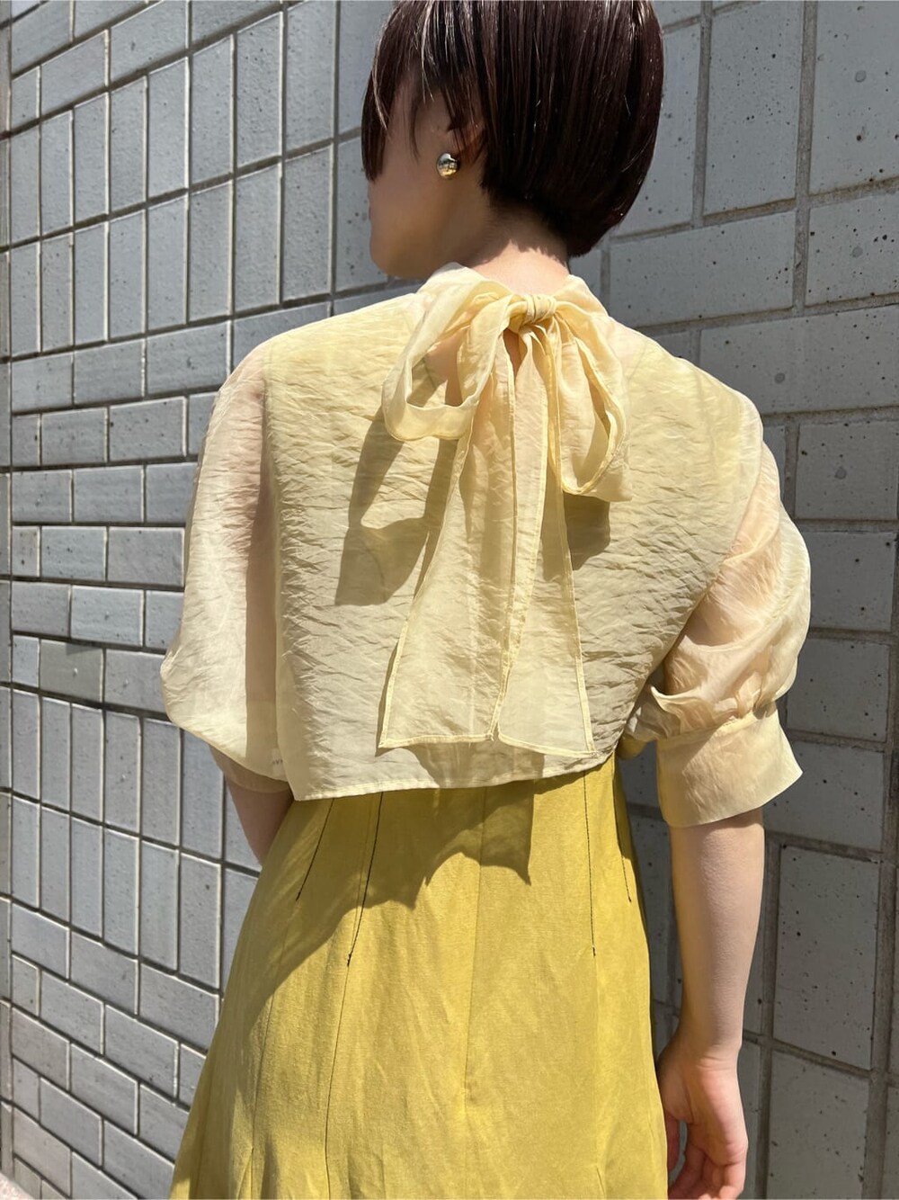 その他のパンプス、イエロー系のワンピース、ゴールド系のバングル/リストバンドを着用したレディースの春コーディネートの5枚目の写真