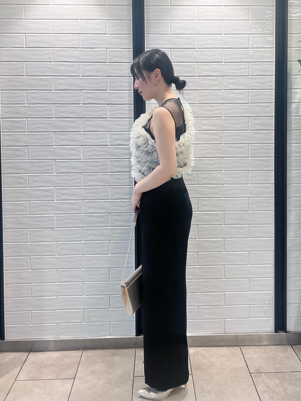 その他のパンツドレス、ゴールド系のパンプス、ゴールド系のクラッチバッグを着用したレディースの春コーディネートの2枚目の写真