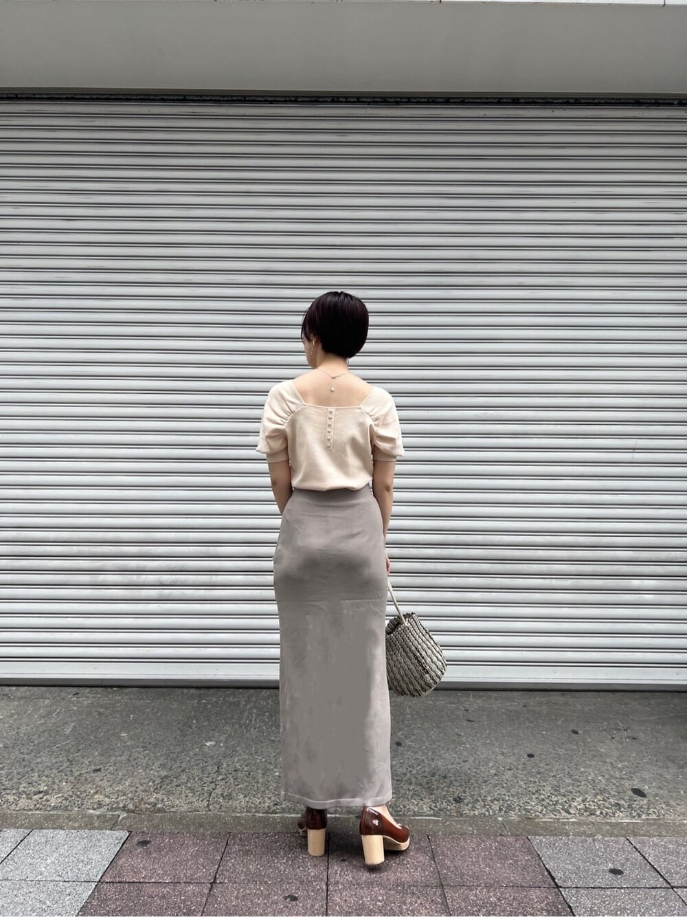 ブラウン系のパンプス、ホワイト系のニット/セーター、ホワイト系のハンドバッグを着用したレディースの夏コーディネートの2枚目の写真