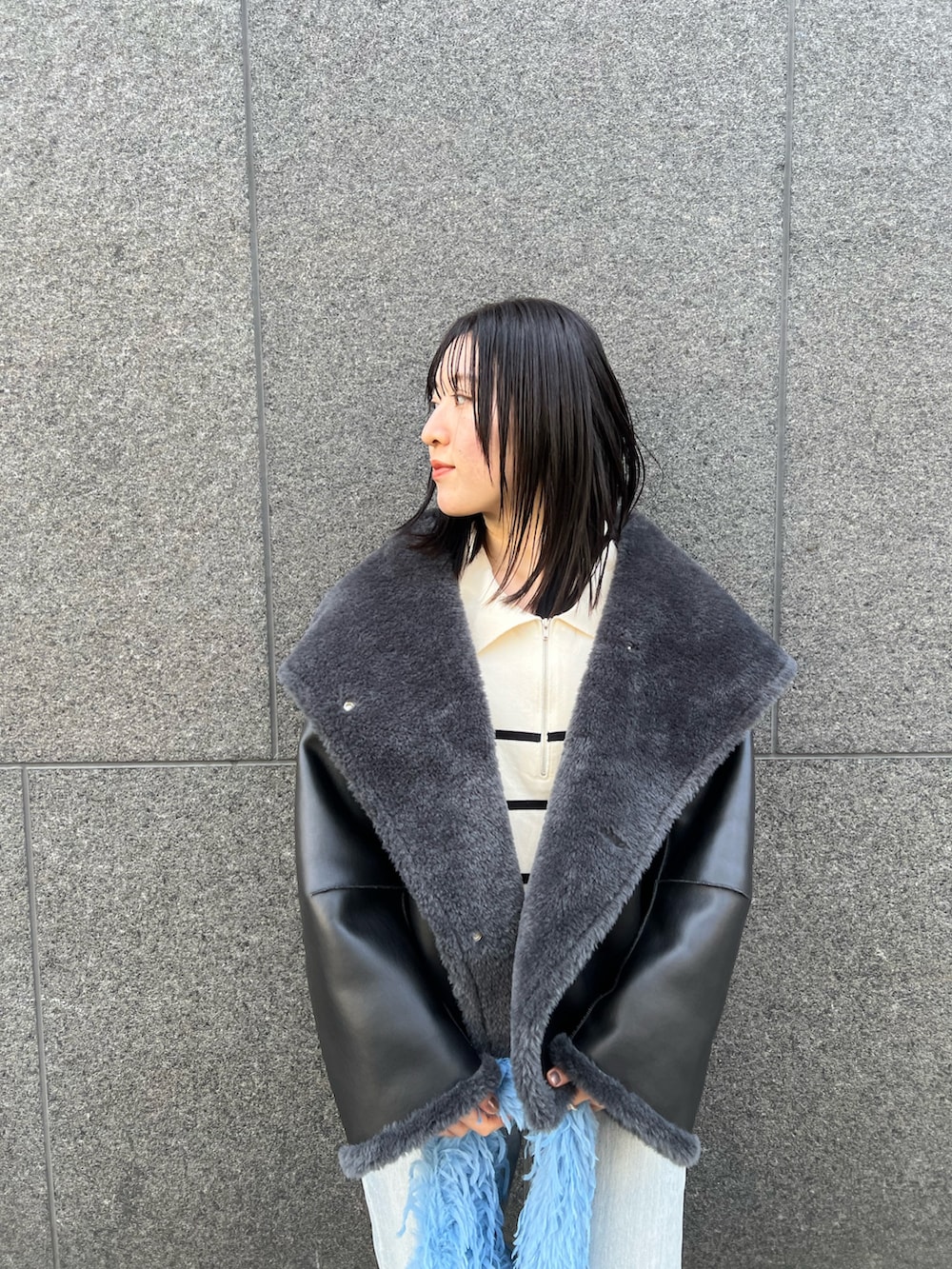 グレー系のムートンコート、ブルー系のデニムパンツを着用したレディースの冬コーディネートの3枚目の写真