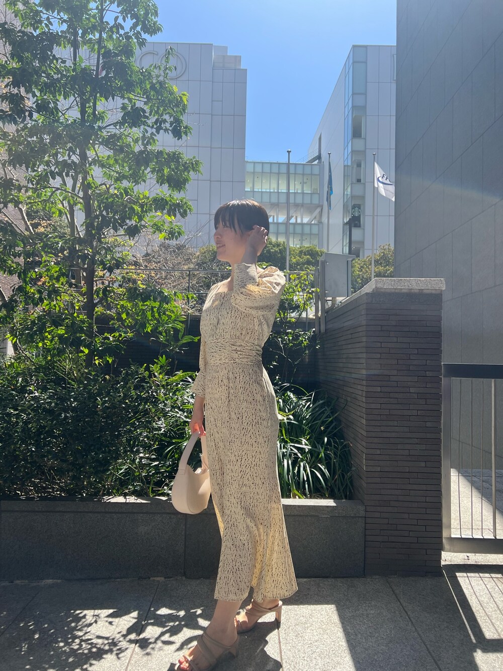 ホワイト系のハンドバッグ、ベージュ系のサンダル、ホワイト系のワンピースを着用したレディースの春コーディネートの6枚目の写真