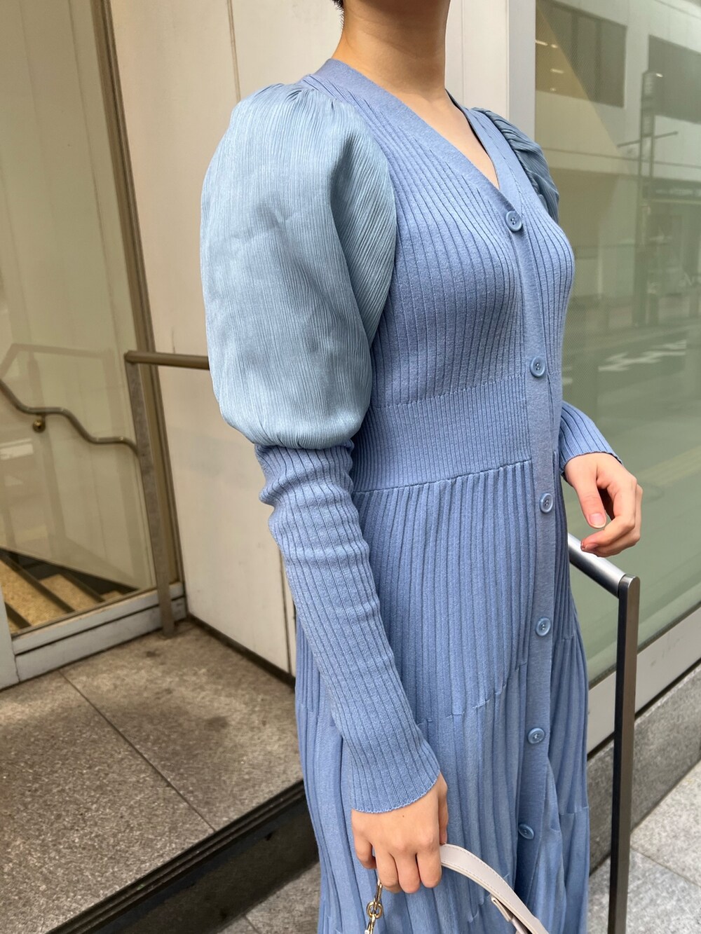 ベージュ系のブーツ、ホワイト系のハンドバッグ、ホワイト系のノーカラーコートを着用したレディースの冬コーディネートの8枚目の写真