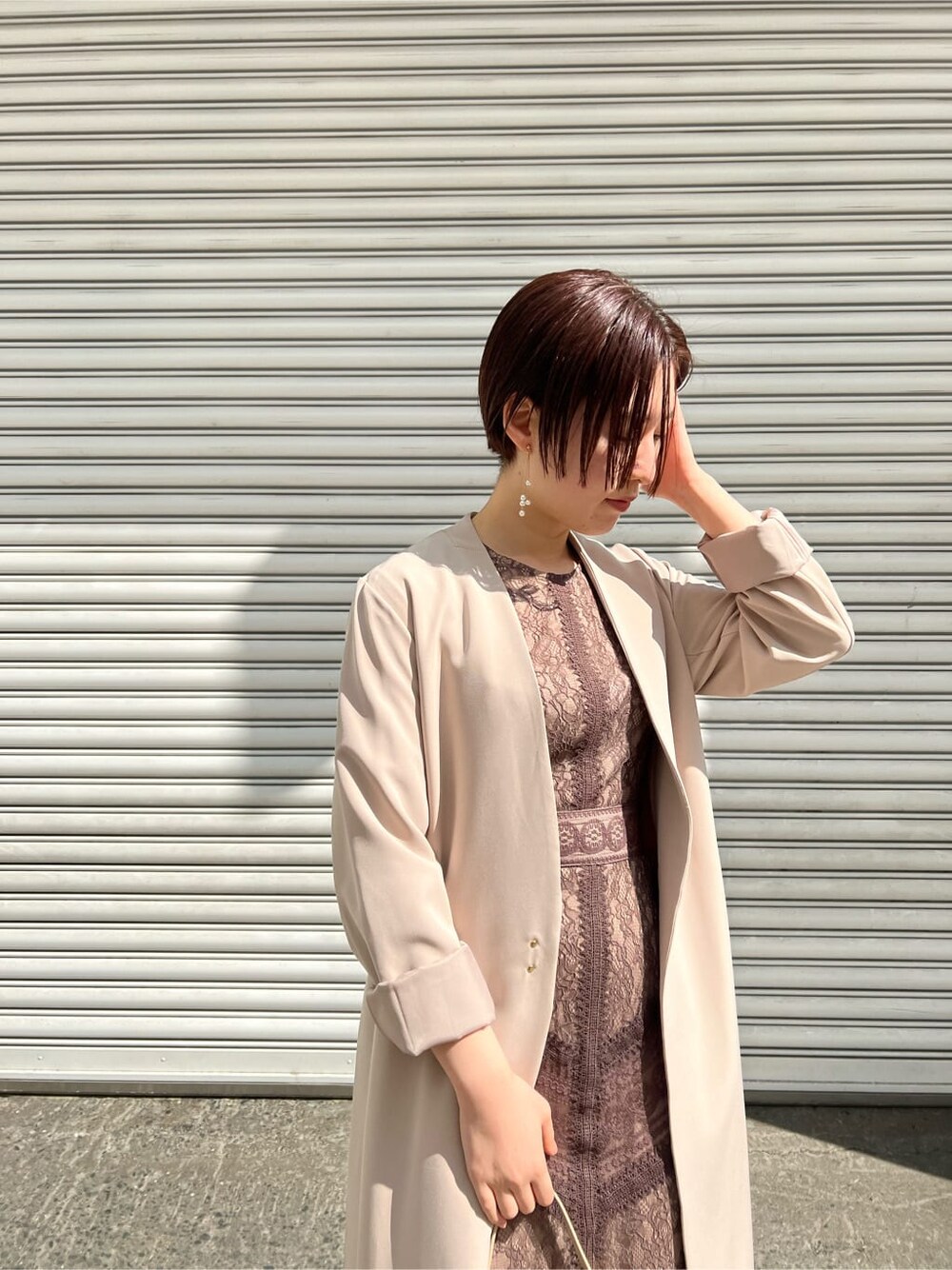 ホワイト系のノーカラーコート、ベージュ系のドレス、ベージュ系のクラッチバッグを着用したレディースの春コーディネートの10枚目の写真