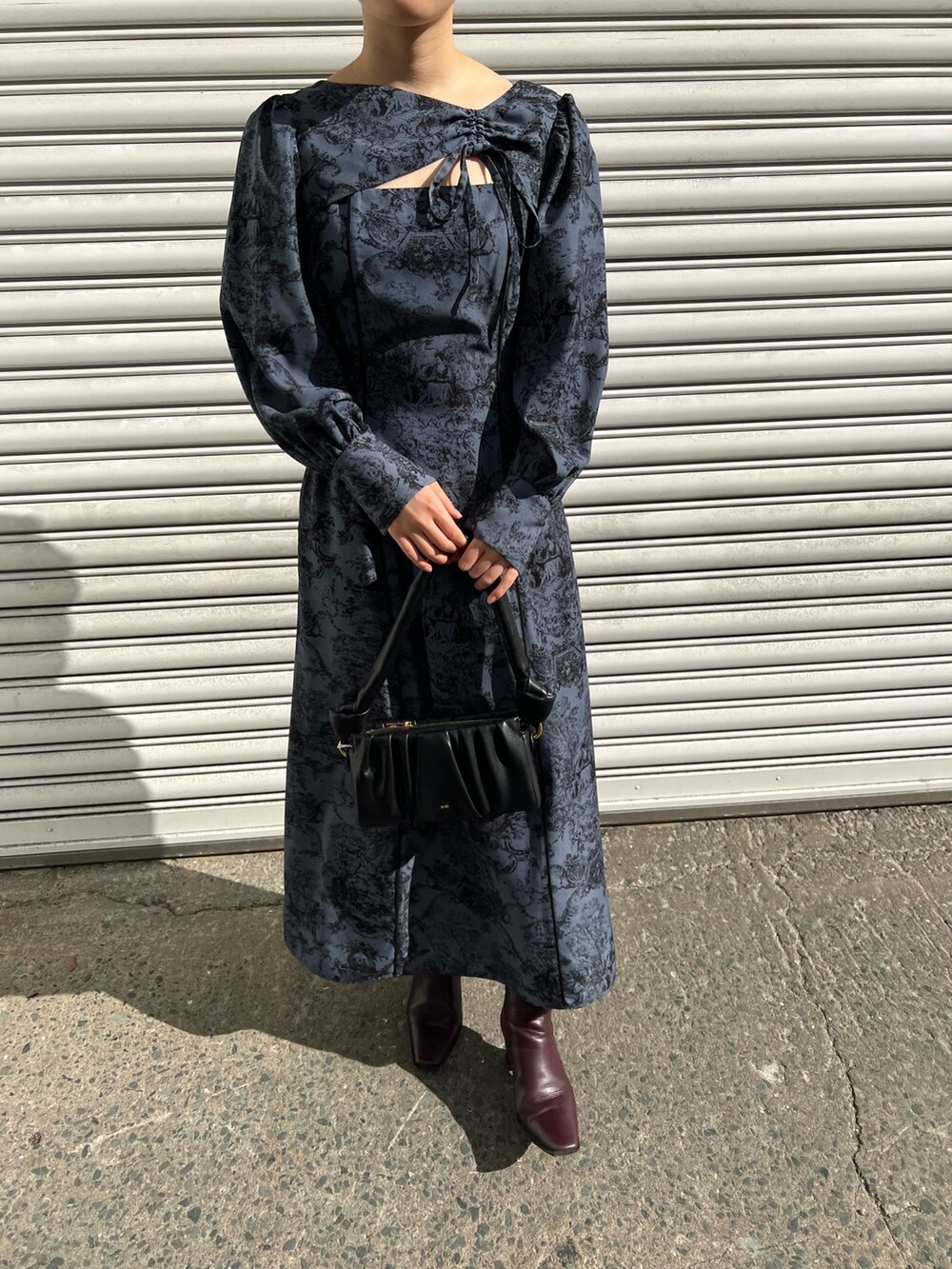 レッド系のブーツ、ブラック系のノーカラーコート、ブルー系のワンピースを着用したレディースの冬コーディネートの7枚目の写真