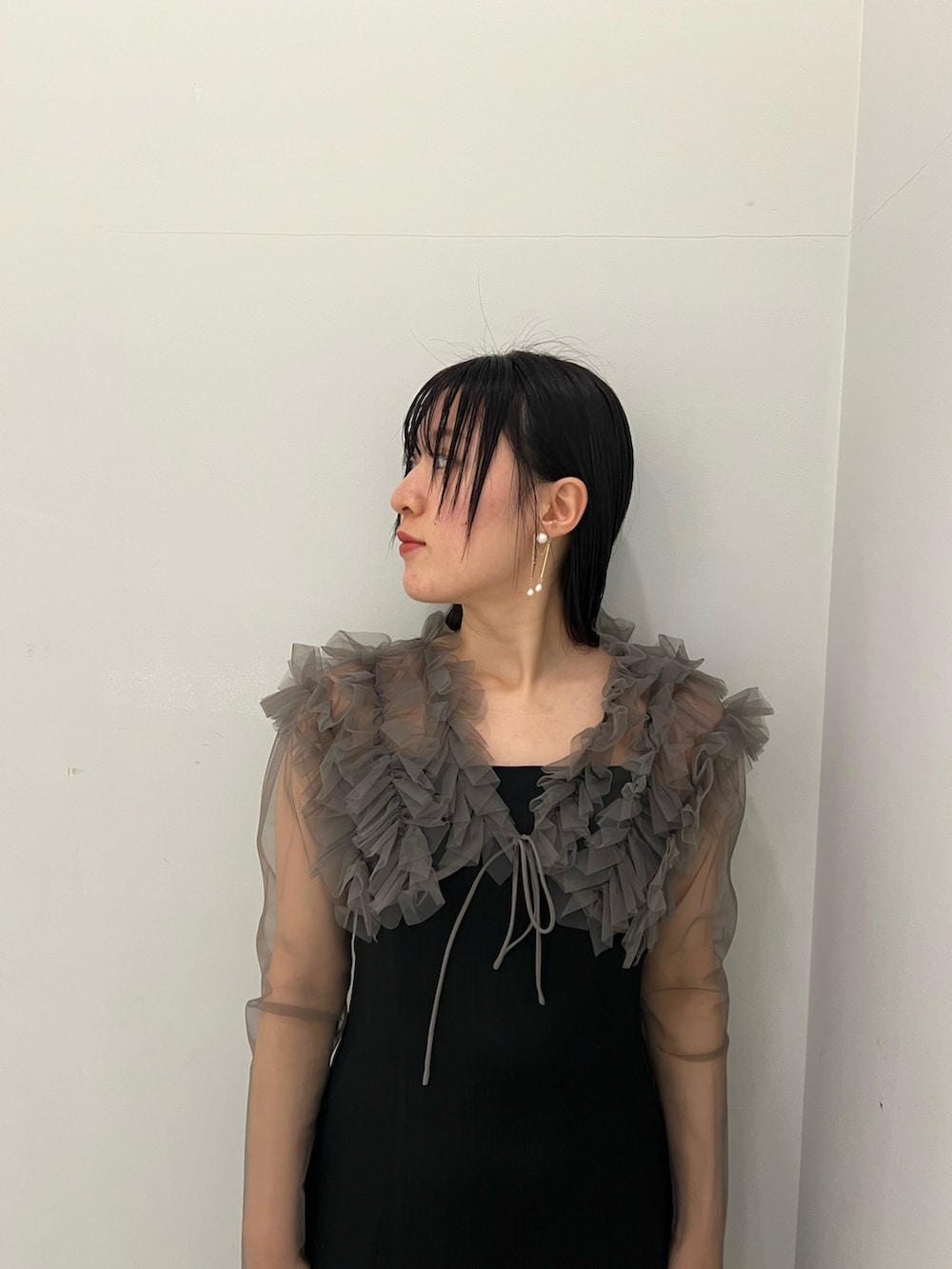 グレー系のドレス、ゴールド系のクラッチバッグ、ゴールド系のパンプスを着用したレディースの春コーディネートの3枚目の写真