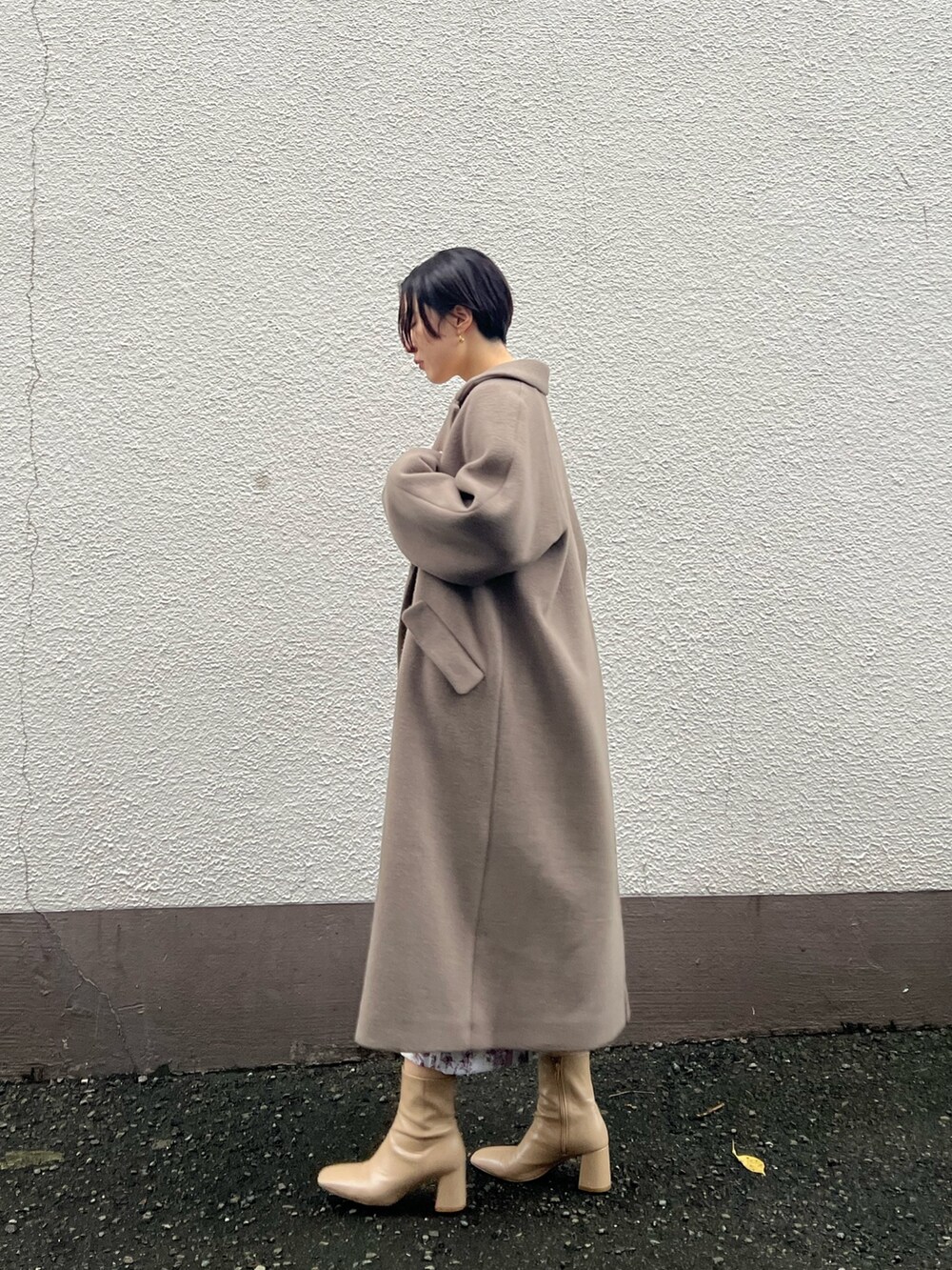 ベージュ系のブーツ、ベージュ系のその他アウター、ホワイト系のニット/セーターを着用したレディースの秋コーディネートの2枚目の写真