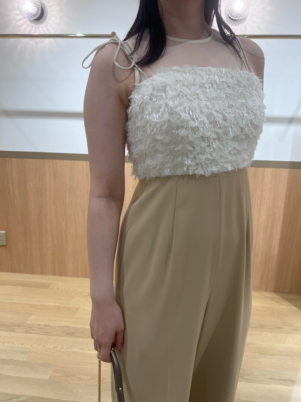 ベージュ系のパンツドレス、ゴールド系のパンプス、ゴールド系のクラッチバッグを着用したレディースの春コーディネートの5枚目の写真