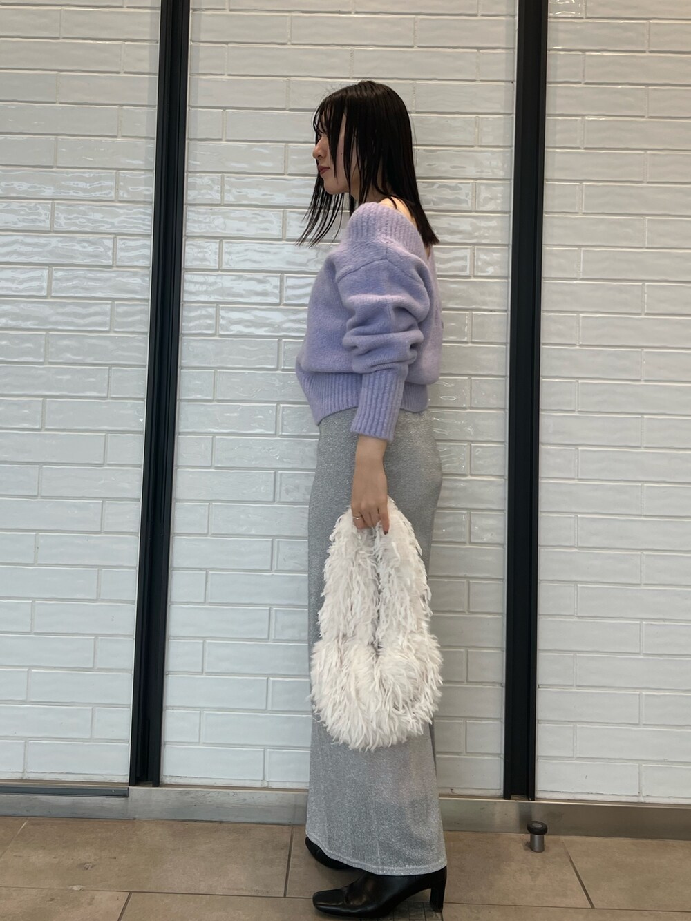 パープル系のニット/セーター、シルバー系のスカートを着用したレディースの冬コーディネートの2枚目の写真
