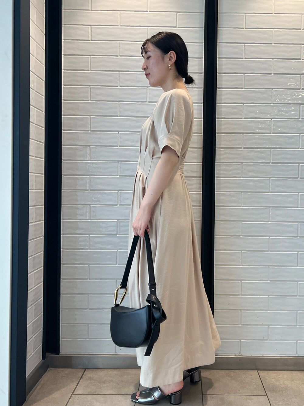 ベージュ系のワンピース、ブラック系のショルダーバッグ、その他のサンダルを着用したレディースの夏コーディネートの2枚目の写真