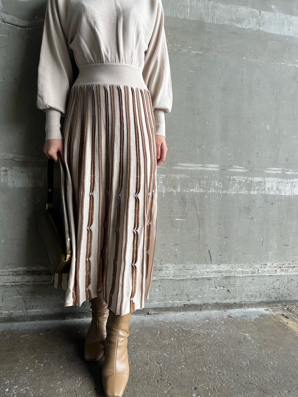 ブラウン系のショルダーバッグ、ベージュ系のブーツ、グレー系のその他アウターを着用したレディースの冬コーディネートの9枚目の写真