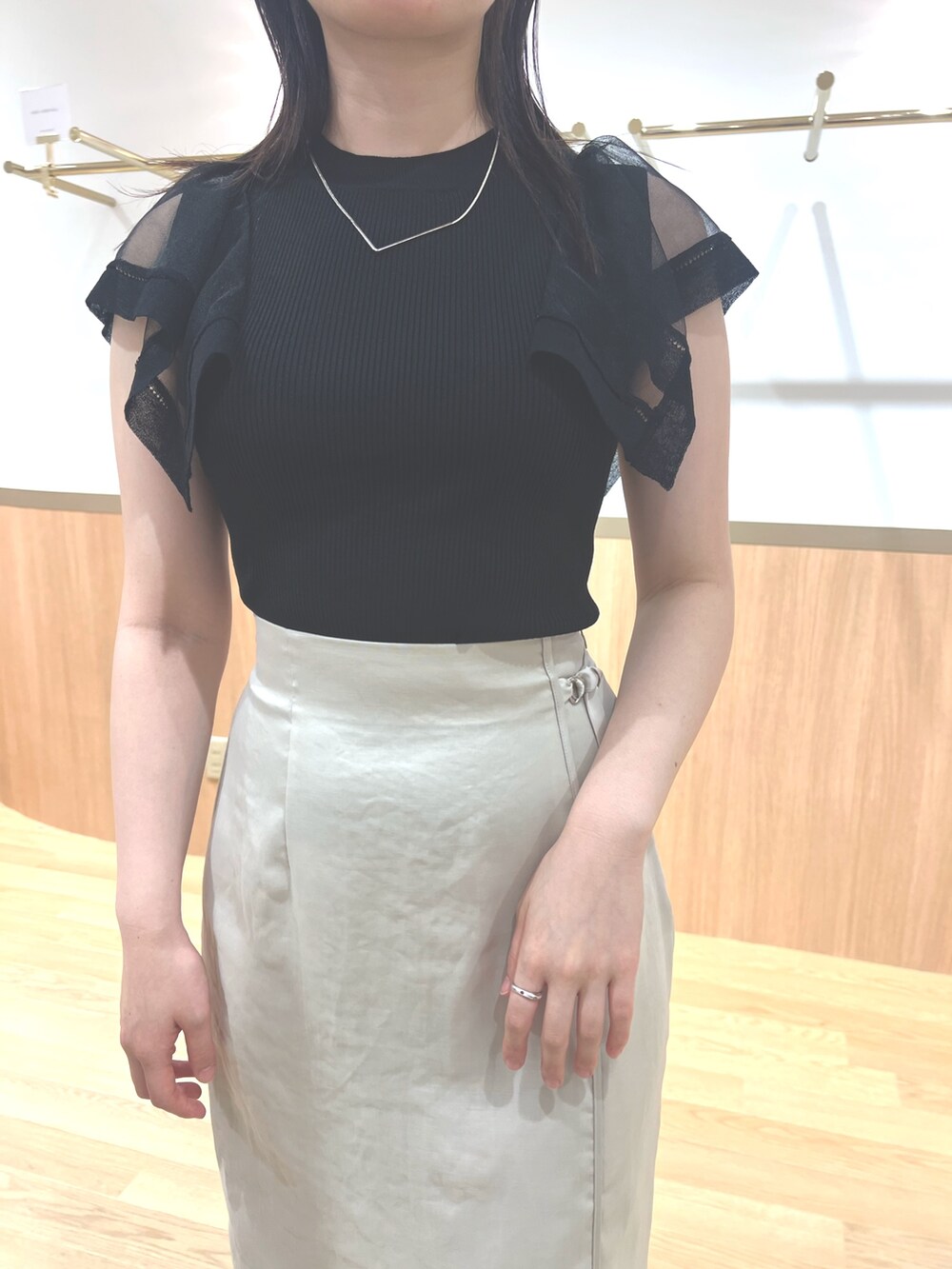 ブラック系のニット/セーター、ホワイト系のスカート、ホワイト系のサンダルを着用したレディースの春コーディネートの4枚目の写真