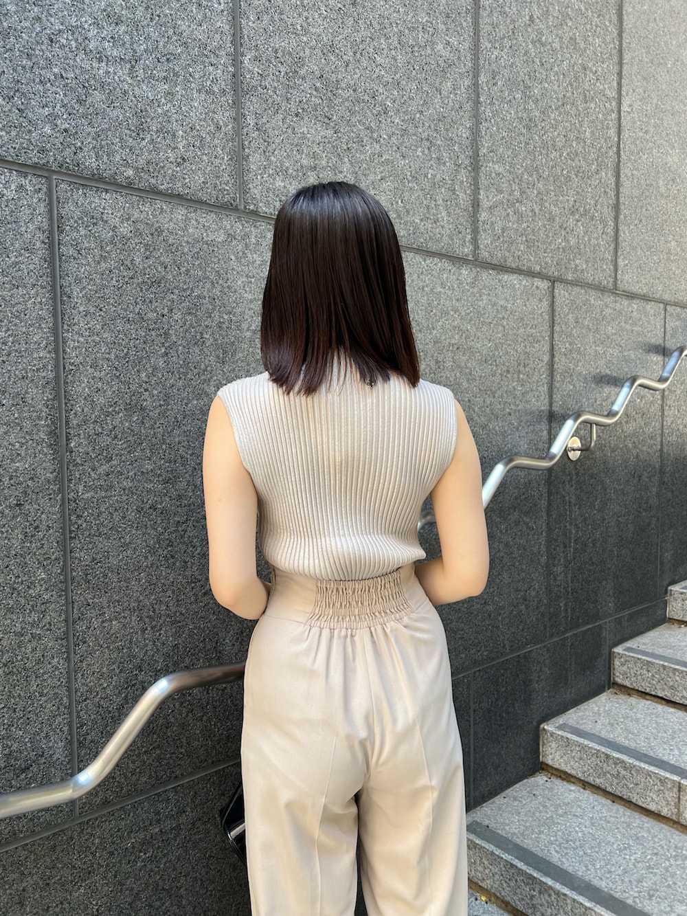 ブラック系のショルダーバッグ、ブラック系のブーツ、ホワイト系のスラックスを着用したレディースの秋コーディネートの7枚目の写真